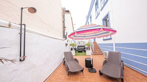 An outdoor patio with two lounge chairs, a striped umbrella, and a hose for a water feature. - El Charco Azul (San Andrés y Sauces)