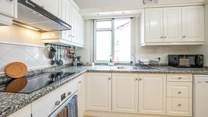 A modern kitchen with white cabinets, a granite countertop, a built-in oven, and a microwave. - El Charco Azul (San Andrés y Sauces)
