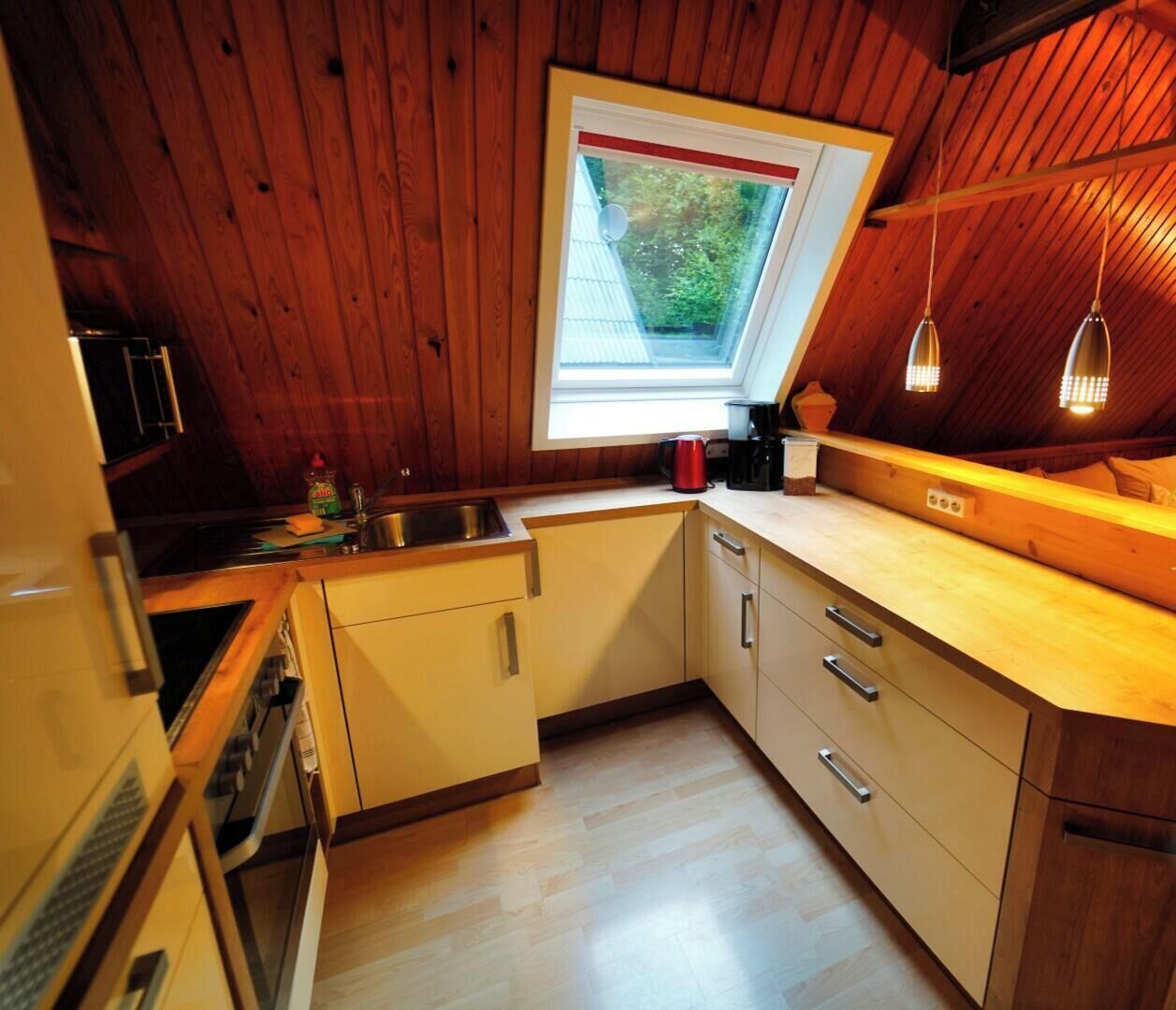 Une cuisine chaleureuse avec des murs en bois, une fenêtre et un plafond en bois.