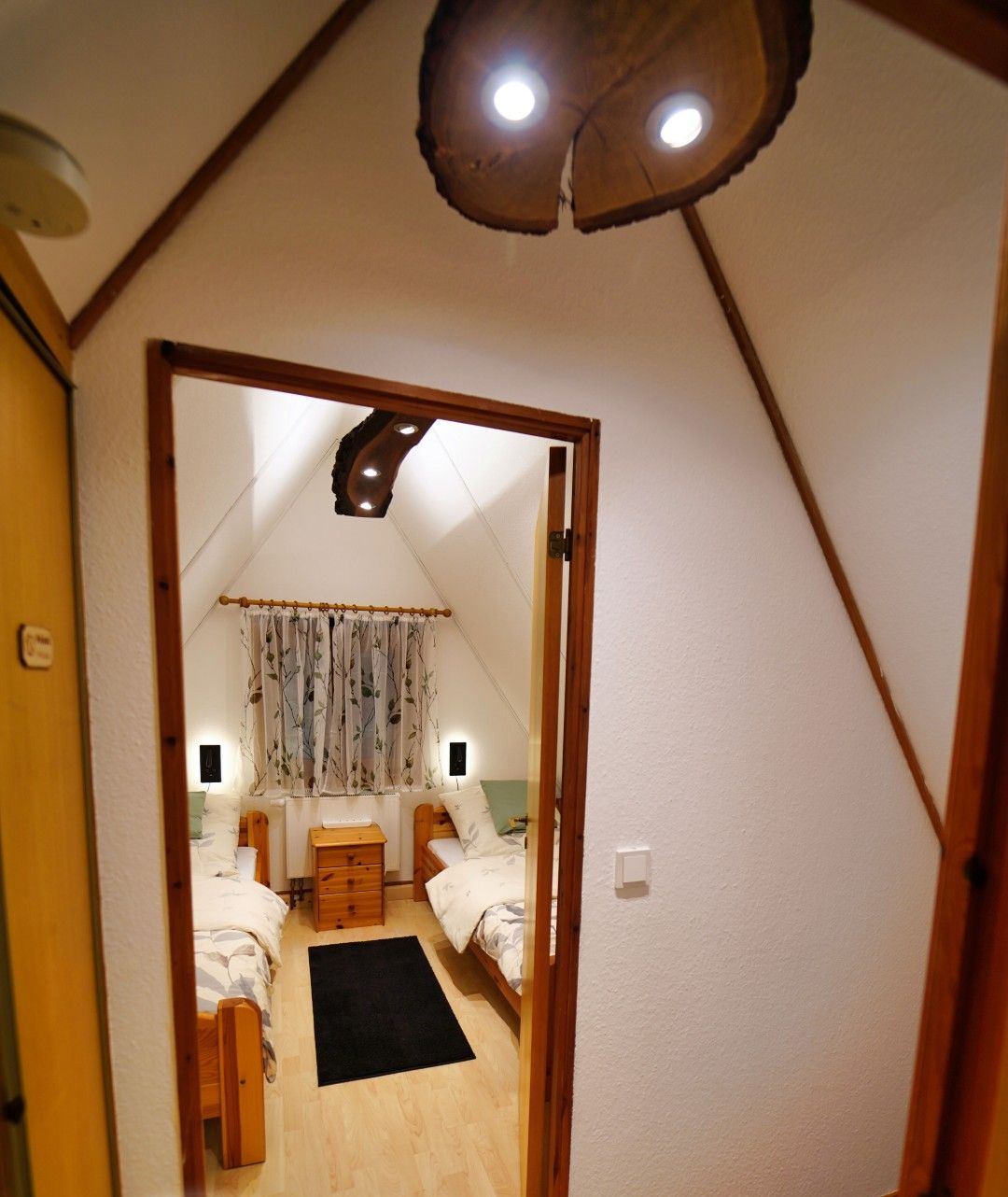 A bedroom with a wooden bed, a bedside table, and a window with curtains.
