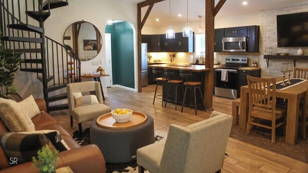 Una cucina moderna con mobili scuri, un'isola centrale e un'area pranzo con sedie e tavolo in legno.