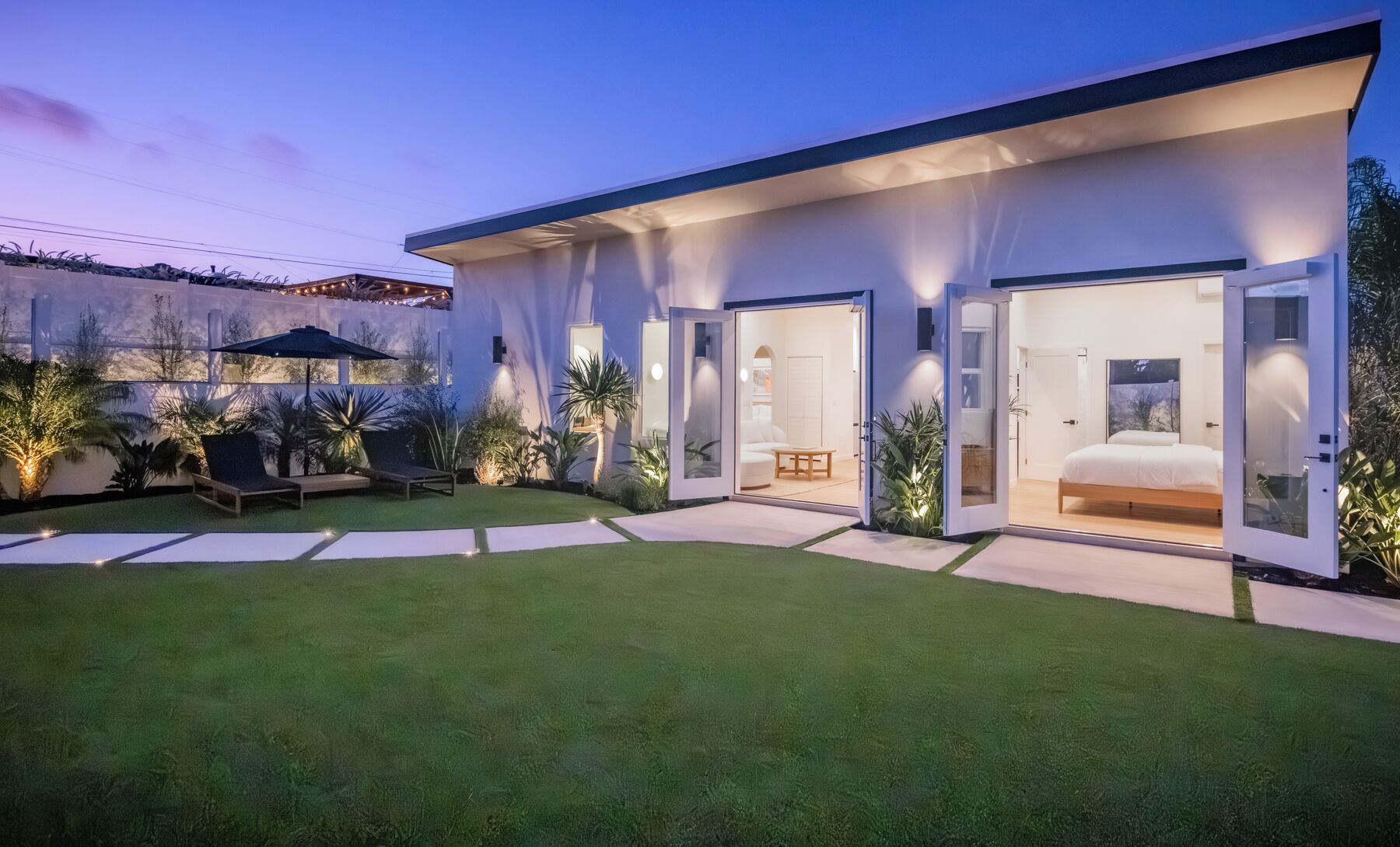 A modern house with a spacious backyard, a well-maintained lawn, and a large bed in the bedroom.