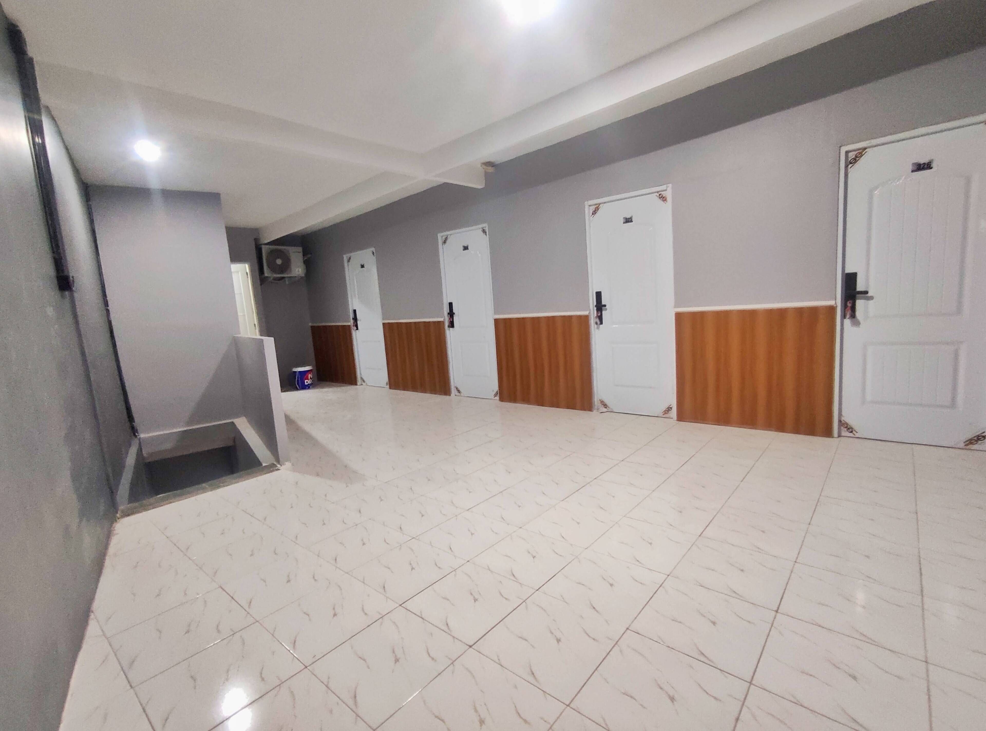 A hallway with white tiled floors, grey walls, and wooden paneling on the lower half of the doors.