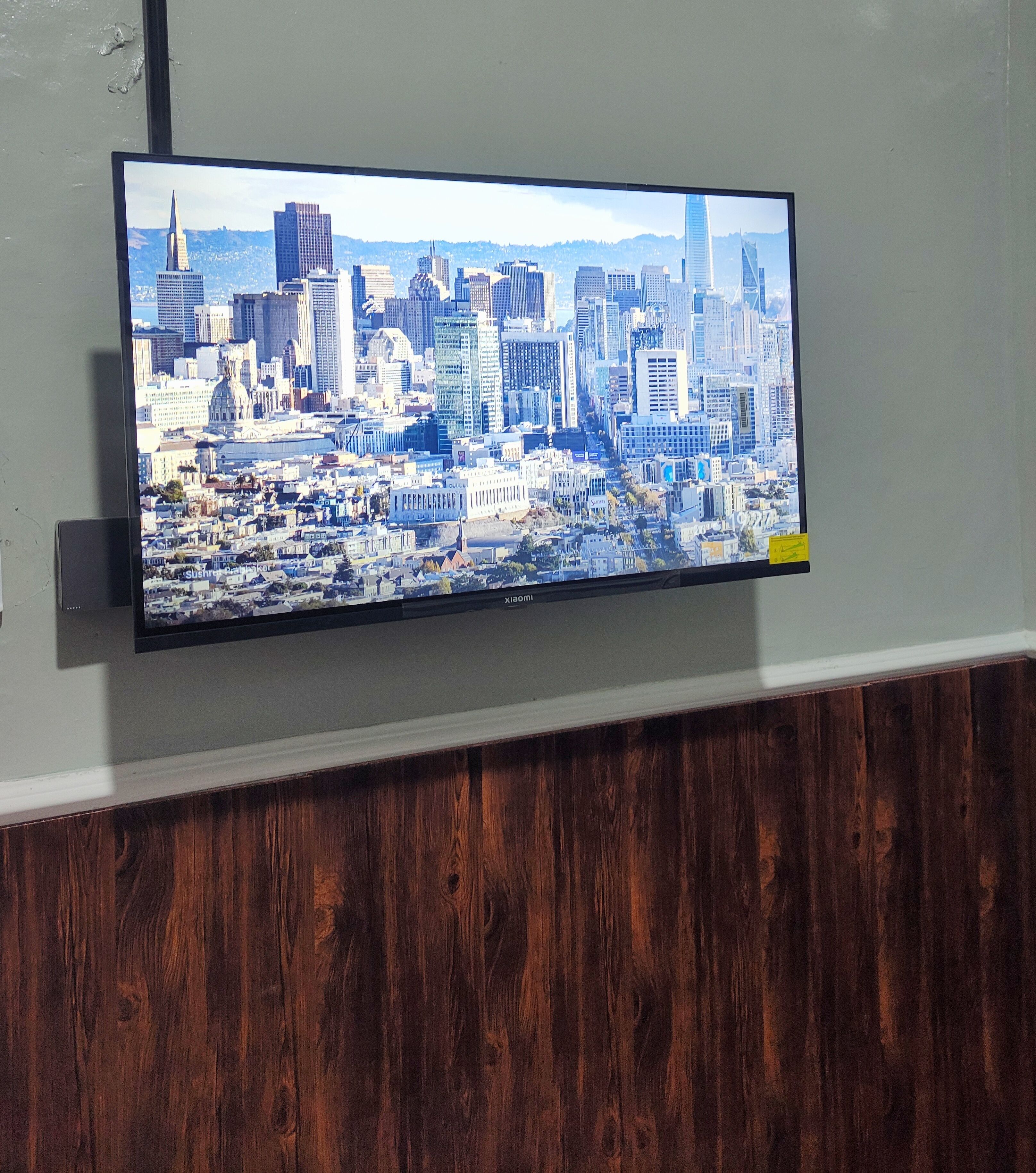 A flat-screen TV mounted on a wall displaying a cityscape.