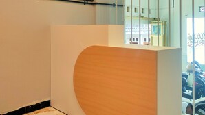 A modern reception desk with a curved design, a glass railing, and a view of parked cars outside. - Semarang Co Stay (Semarang)
