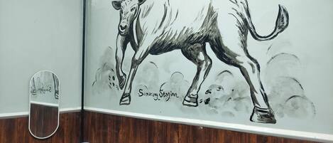 A wall mural of a bull, a wooden bench, and a small table with a cup.