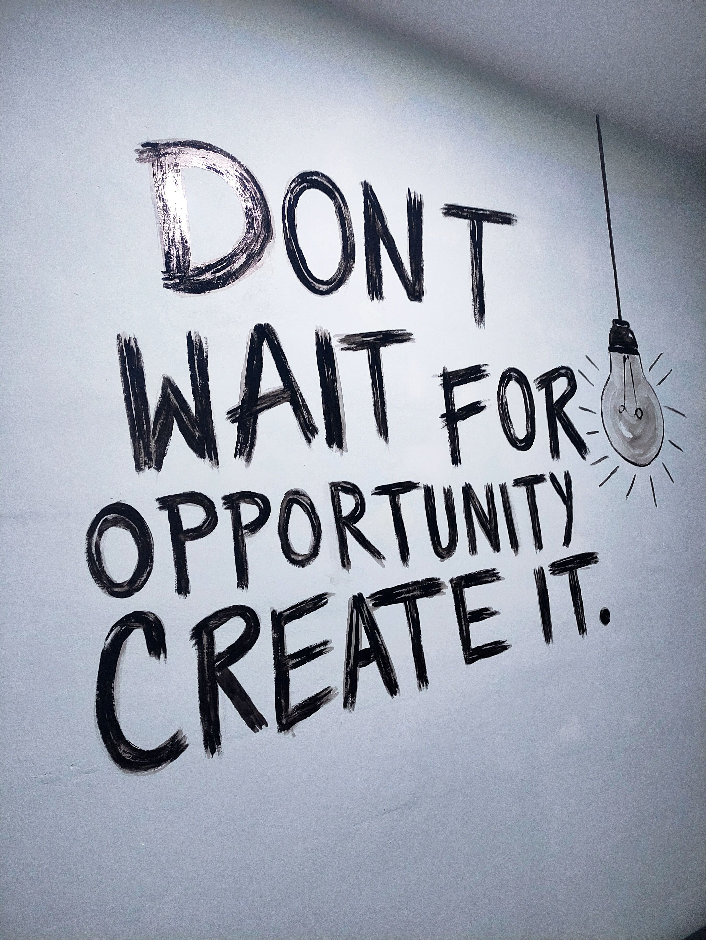 Una frase motivacional en una pared blanca: "NO ESPERES A LA OPORTUNIDAD, ¡HAZLA!"