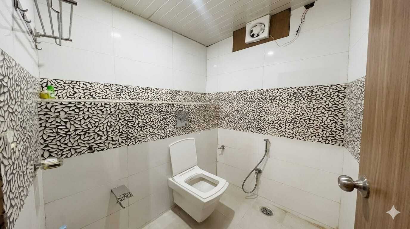 A small bathroom with a toilet, shower, and a patterned tile design.