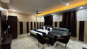 A hotel room with a bed, a sofa, a small table, and chairs. - Hotel Kings Paradise & Banquet (Lucknow)