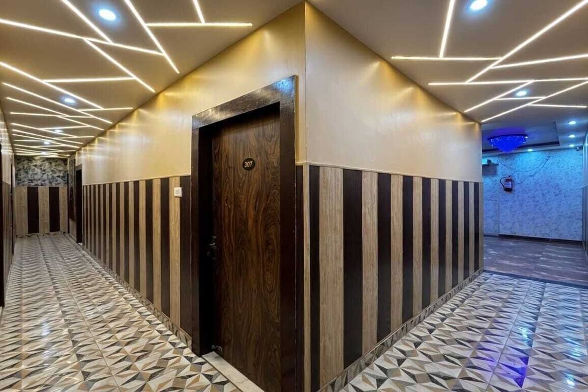 A hallway with a geometric patterned floor, a wooden door with a number, and a modern ceiling design.