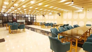 A spacious dining area with multiple tables and chairs, a polished floor, and a modern ceiling design. - Hotel Kings Paradise & Banquet (Lucknow)