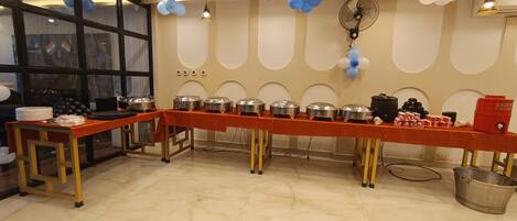Montaje de bufé con varias estaciones de servicio, un ventilador y globos en la pared.