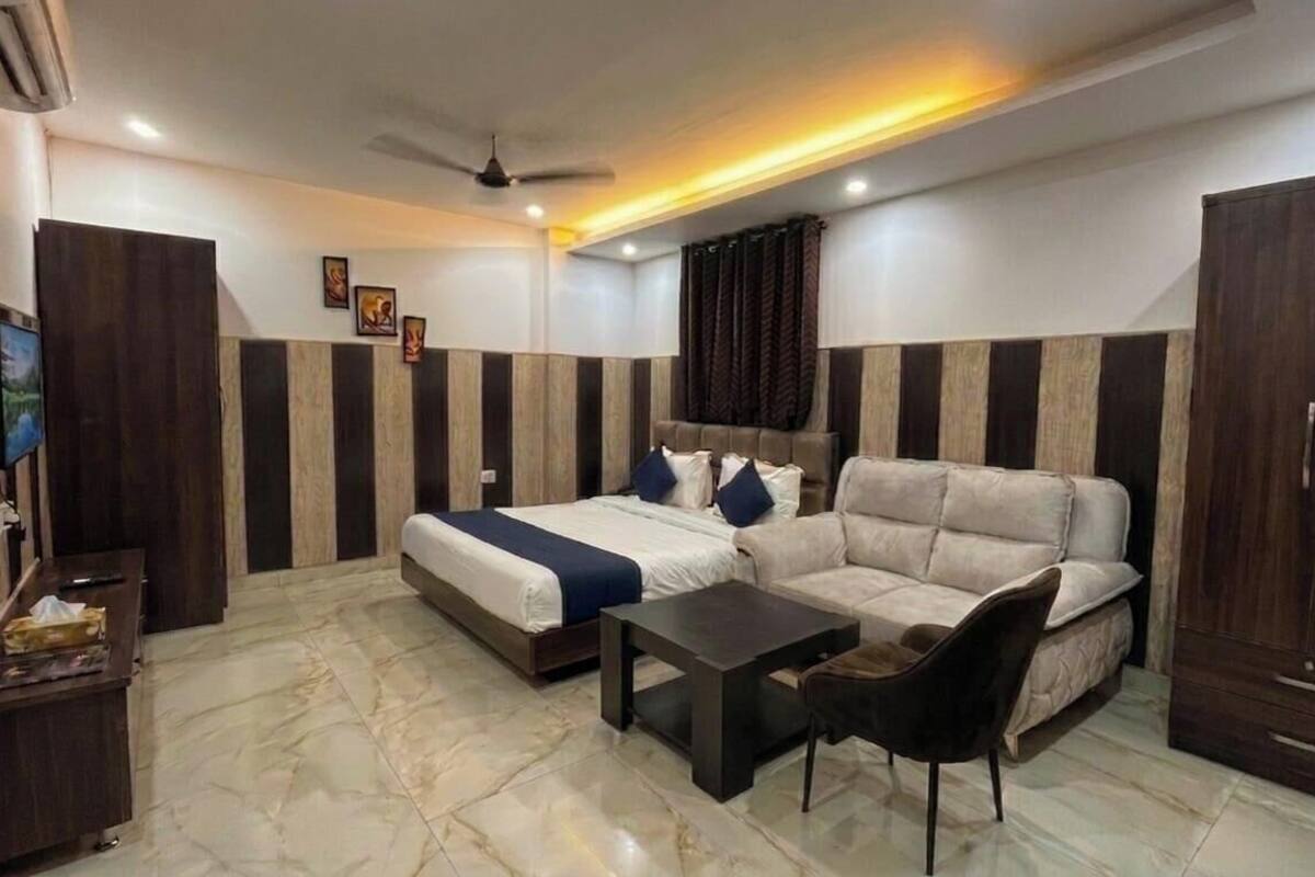 A hotel room with a bed, sofa, TV, desk, and wardrobe.