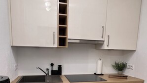 A modern kitchen with white cabinets, a black stove, and a wooden countertop. - Alpenruhe Vacation Rental with Exceptional Mountain Views, Pool, and Sauna (Scheidegg)