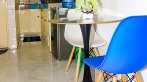 Une cuisine moderne avec des meubles blancs, un distributeur d’eau bleu et une petite table accompagnée d’une chaise bleue.