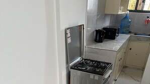 Une cuisine compacte équipée d’un réfrigérateur, d’une cuisinière et d’un distributeur d’eau.
