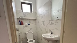 Une salle de bain avec des toilettes, un lavabo et une fenêtre.