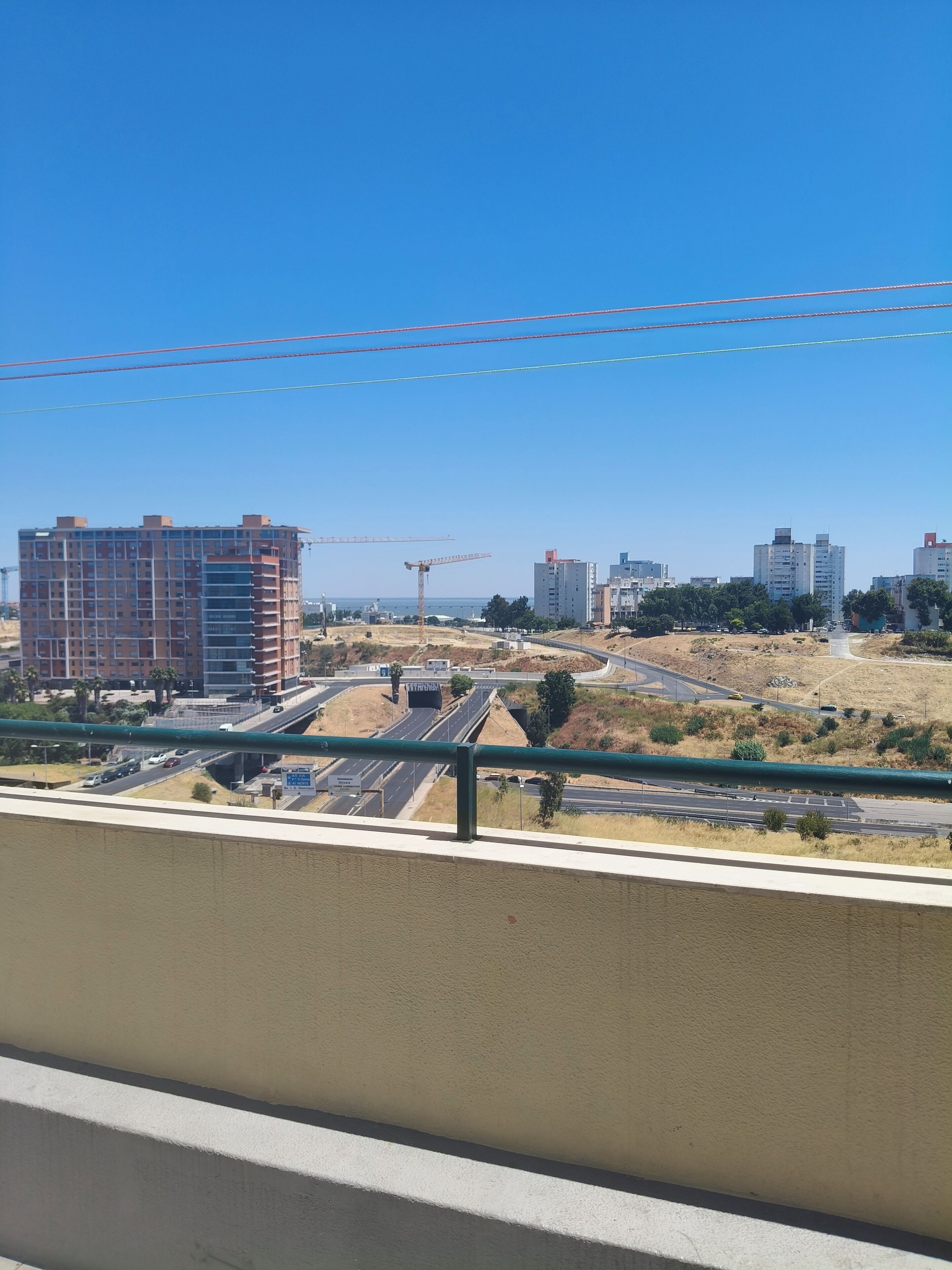 Eine Baustelle mit einem mehrstöckigen Gebäude im Bau, einer Autobahn mit Fahrzeugen und einem strahlend blauen Himmel.