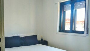 A single bed with white linens, a dark headboard, and a blue accent wall.