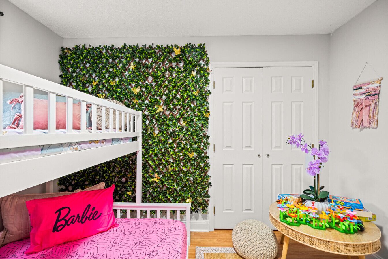 Habitación infantil con literas, un muro decorativo, una puerta y una mesita llena de juguetes.