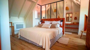 A bedroom with a bed, a wooden headboard, a large mirror, a bedside table, and a window.