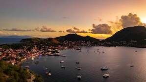 A coastal town with a marina filled with boats, surrounded by hills and a clear sky.
