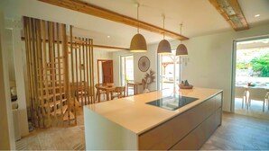 A modern kitchen with a central island, pendant lighting, and a view of the outdoors.