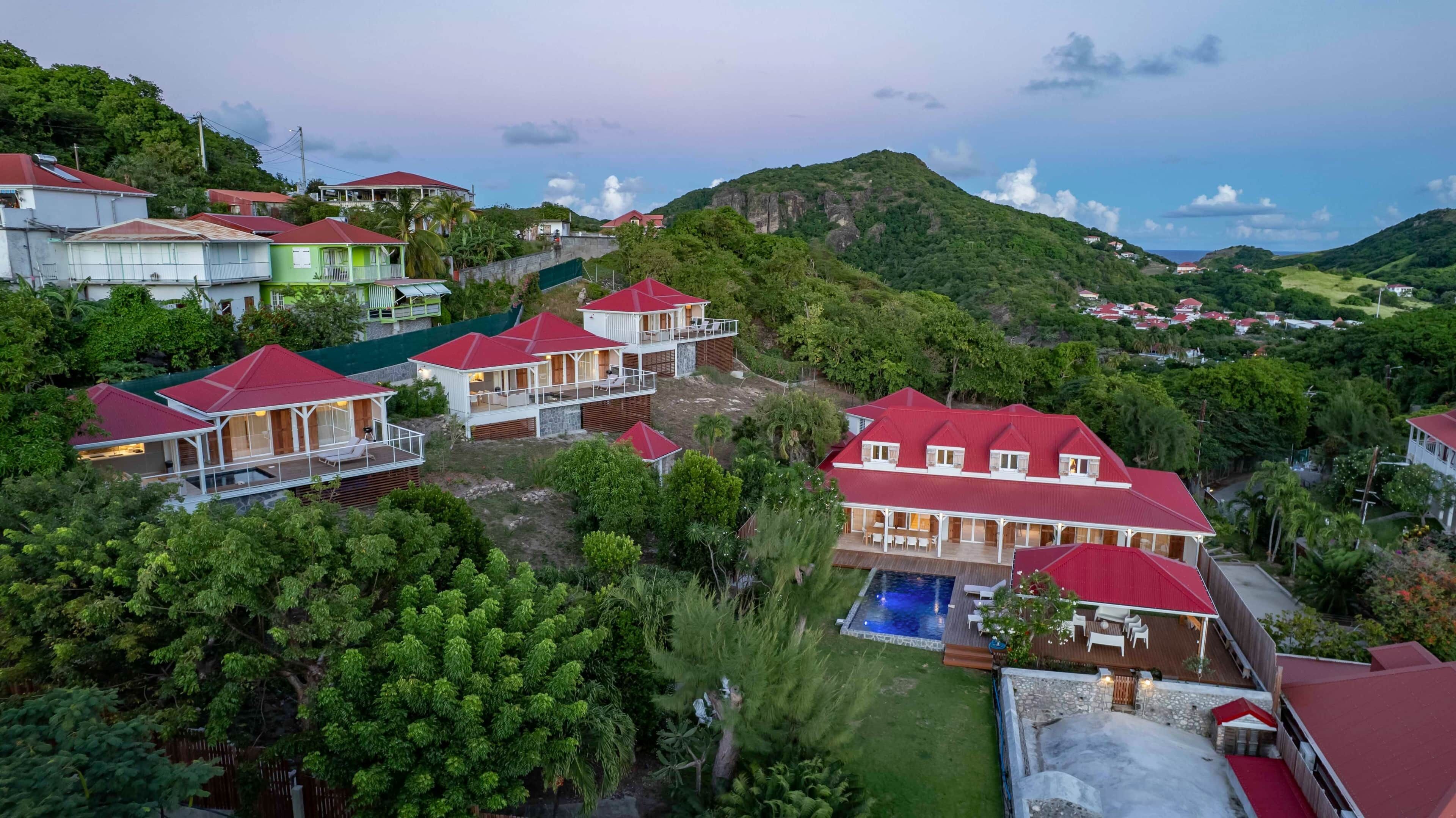 A resort with multiple buildings, a swimming pool, and lush greenery.