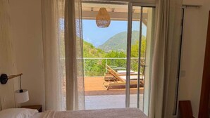 Une chambre à coucher comprenant un lit, une table de chevet, une lampe et une vue sur un balcon avec une chaise en bois et une table.