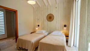 Une chambre avec deux lits, des murs en bois, un élément de décoration circulaire au mur et des lampes de chevet.