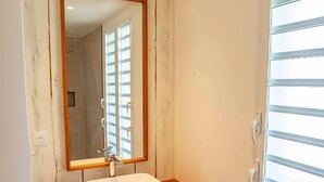 Une salle de bain avec un meuble-lavabo en bois, un lavabo blanc et un grand miroir.