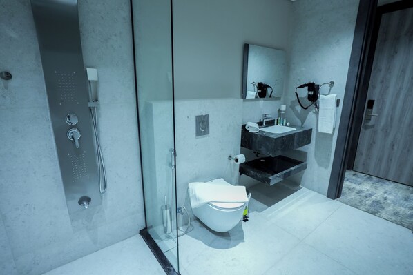 Et moderne badeværelse med en glasafskærmet brusekabine, et hvidt toilet, en sort vask og en bordplade i marmor.