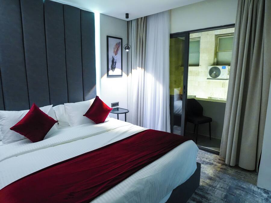 Habitación de hotel con una cama grande, una mesita pequeña y vistas al exterior a través de un ventanal.
