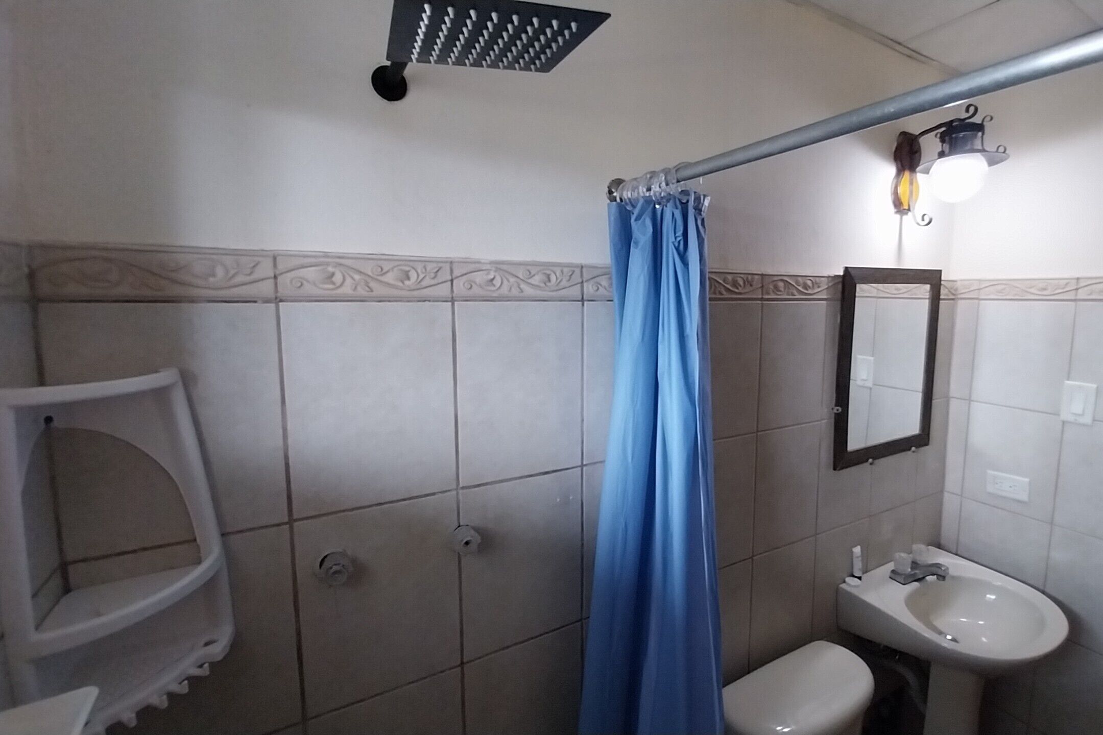 A bathroom with a shower, toilet, sink, and a towel rack.