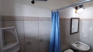 A bathroom with a shower, toilet, sink, and a towel rack.