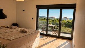 Un dormitorio con una cama grande, un escritorio y vistas a un balcón con mobiliario exterior.