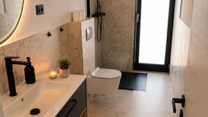 Un baño moderno con lavamanos, espejo y ducha.