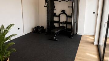 Ein Heimfitnessraum mit Klimmzugstange, Gewichtbank und verschiedenen Trainingsgeräten.