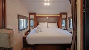 Een kleine, goed verlichte slaapkamer met een groot bed, houten hoofdbord en een klein nachtkastje.