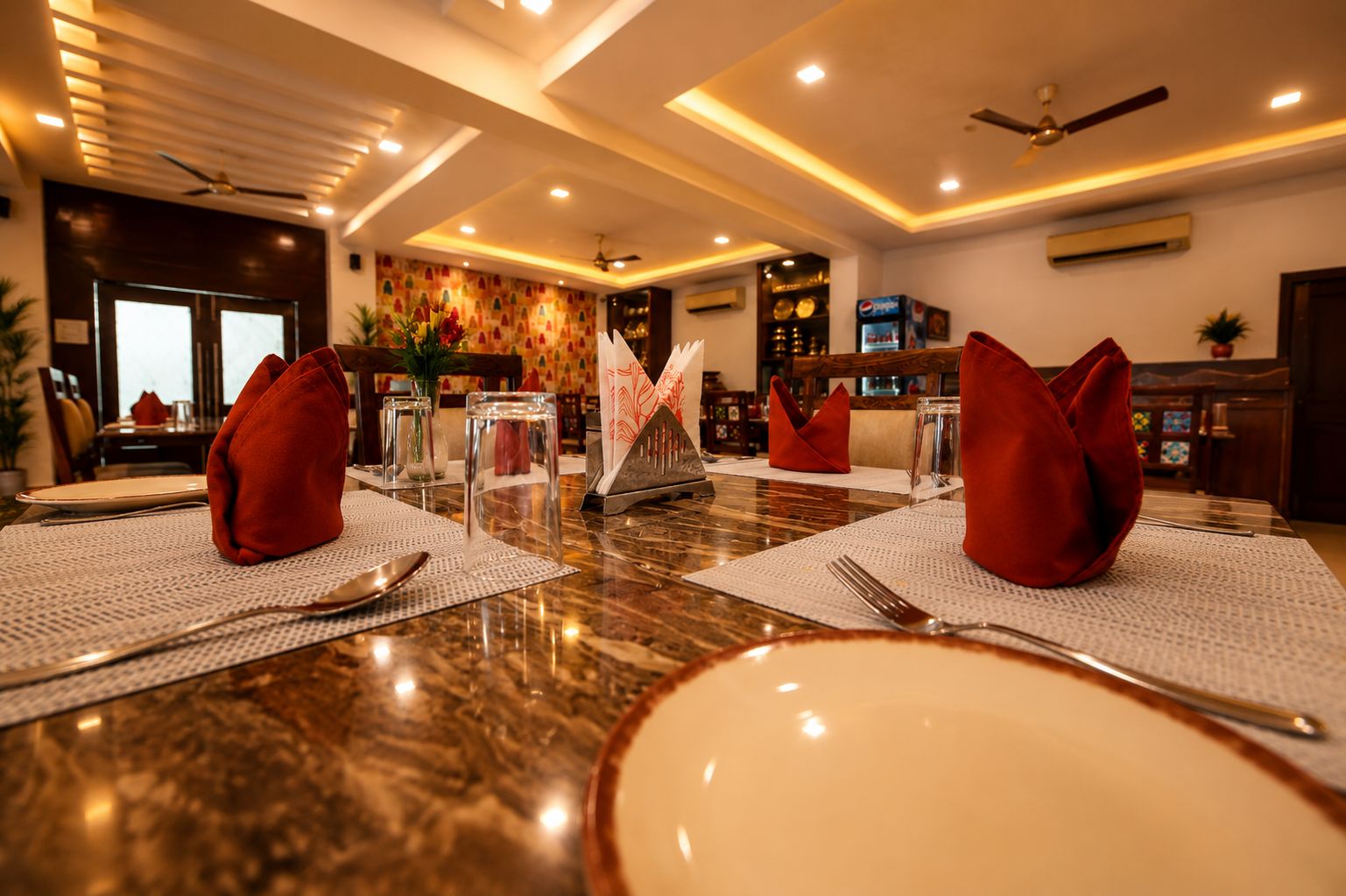 A dining table set with red napkins, clear glassware, and a decorative centerpiece.