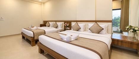 A hotel room with two beds, a wooden headboard, a bedside table, and a large mirror.