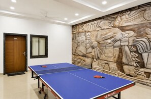 Una habitación con mesa de ping pong, una puerta con la etiqueta '101' y un relieve decorativo en la pared.