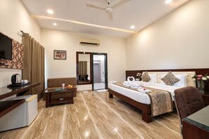 A hotel room with a bed, a desk, a chair, a sofa, and a television. - The Elegance Resort (Chittorgarh)