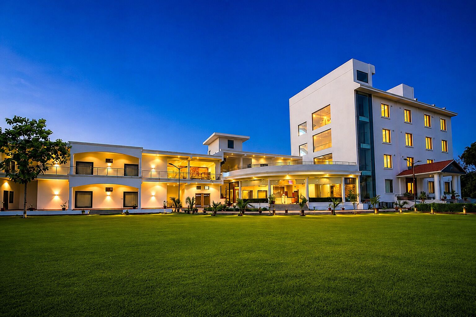 Un hotel de varios pisos con una entrada bien iluminada y un césped delantero.