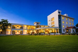 Un hotel de varios pisos con una entrada bien iluminada y un césped delantero.