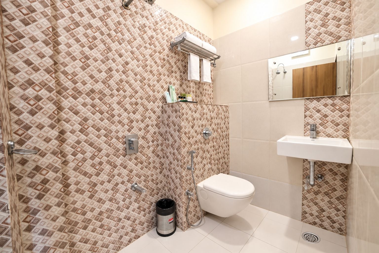 A bathroom with a patterned tile wall, a toilet, a sink, and a shower area.