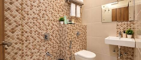 Un bagno con parete rivestita di piastrelle decorate, un WC, un lavandino e uno spazio doccia.
