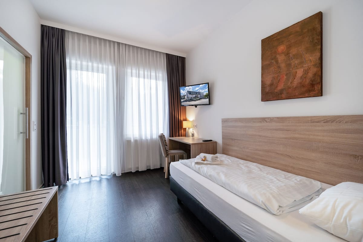 Een hotelkamer met een bed, een bureau, een stoel, een televisie en een schilderij aan de muur.