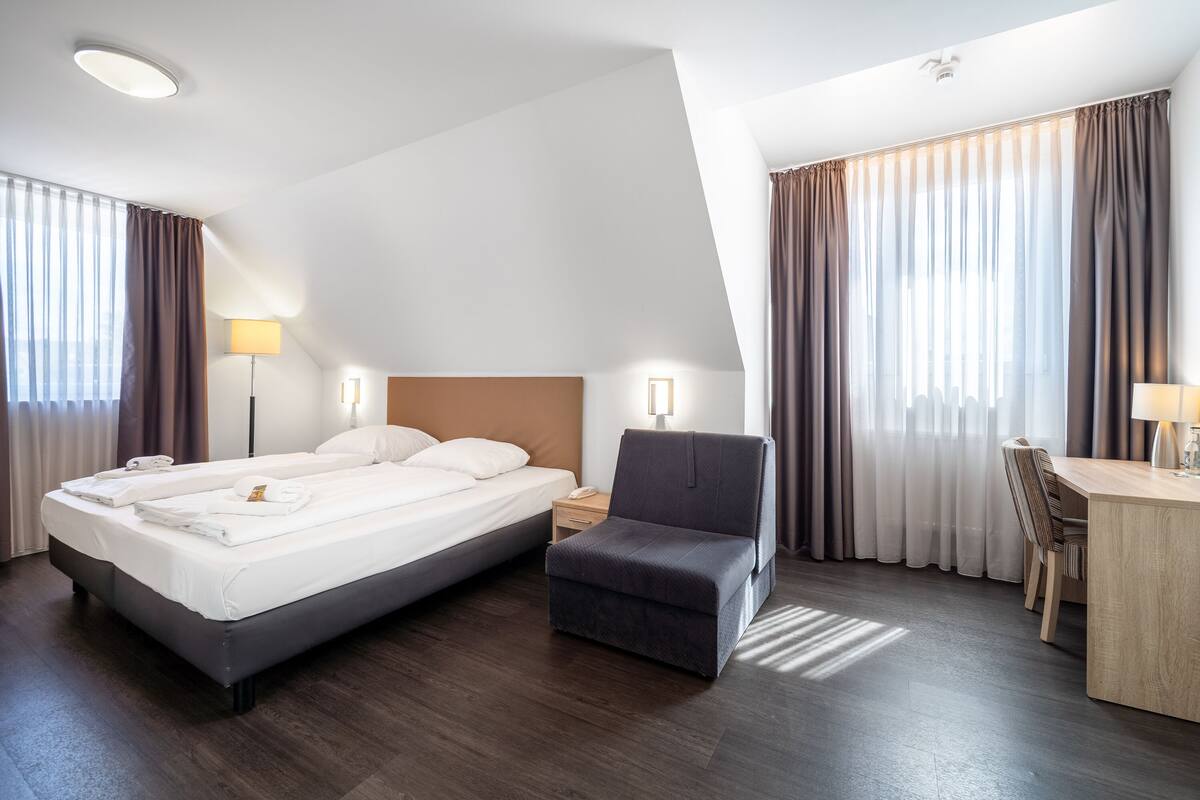 Een hotelkamer met een groot bed, een bureau, een stoel en een kleine bank.