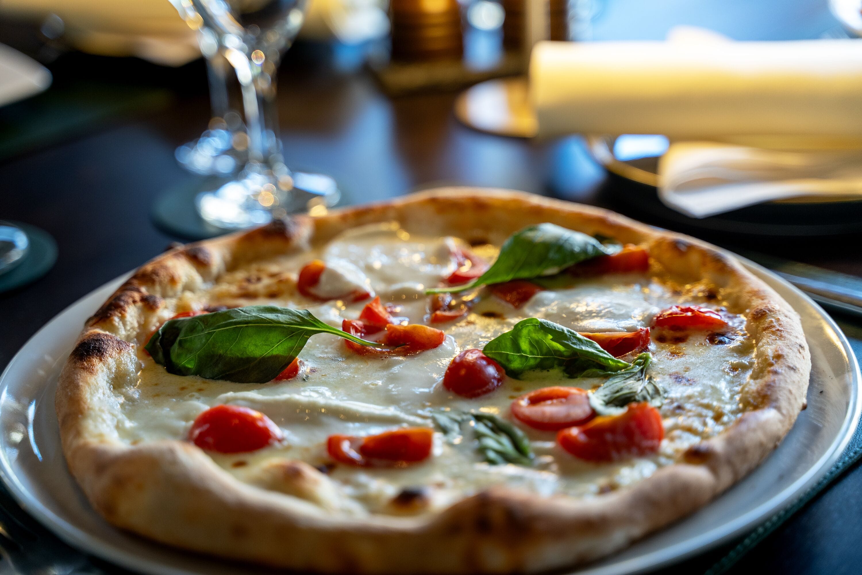 A pizza with cheese, tomatoes, and basil on a plate.